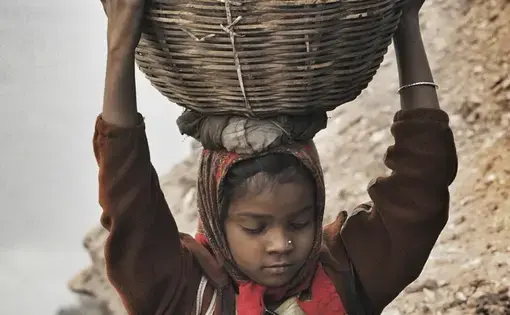 A young girl carries scavenged coal from the bottom of the Alkusha Coalfield.