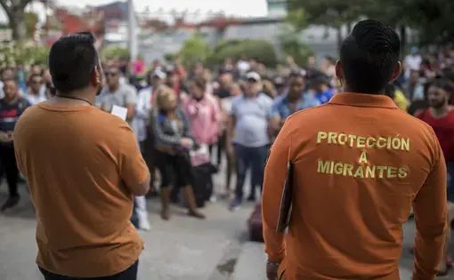 Workers from the Centro de Atención Integral a Migrantes (CAIM) call out numbers from the asylum waiting list outside the center in Ciudad Juárez on May 13, 2019. Image by Ivan Pierre Aguirre. Mexico, 2019.
