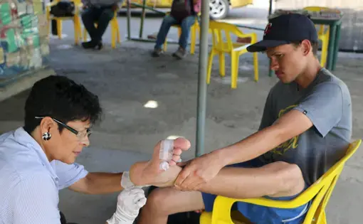 Marta Alcon tends to a Venezuelan caminante that arrived at her shelter in Los Patios, Colombia. Image by Patrick Ammerman. Colombia, 2019.