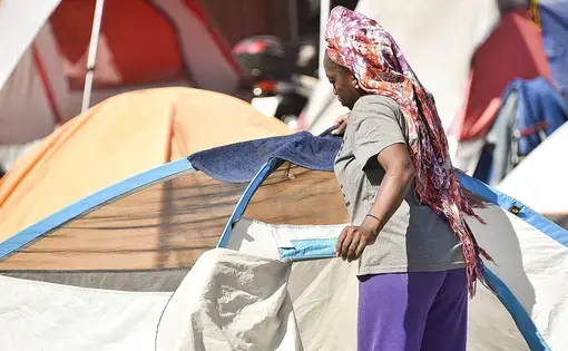 A woman in the Lots, a homeless encampment in Phoenix, drapes a towel over her tent on June 24, when the high in Phoenix hit 111 degrees. Donated tents are available for homeless people who don’t have their own. Image by Steve Carr/Human Services Campus. United States, 2020.