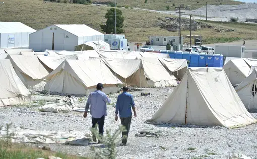 Many were evacuated to camps like this one, in Larisa, Greece. It’s located on a fenced gravel lot dotted with tents, off the side of a divided highway lined by fields the color of sand, over three-hours drive from Athens in one of the hottest, driest parts of the country. More than 800 Afghans and Syrians were deposited here, in the middle of nowhere, by government busses months ago, with no information on why or for how long. Image by Frederick Atax.