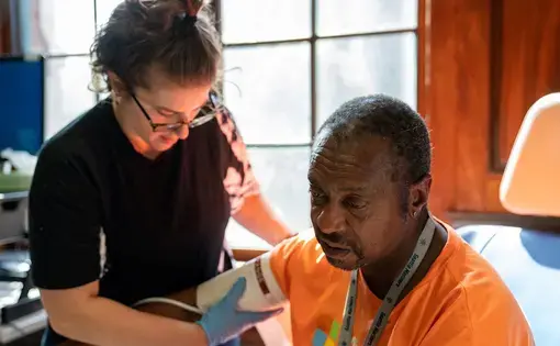 Annie Valenciano, manager of the Downtown Emergency Service Center in Seattle, checks on a client on July 24, 2019. In response to the pandemic, the organization spent nearly $12,000 on smartphones, tablets and laptops so clients could access telehealth services while adhering to shelter-in-place mandates. Image courtesy of Downtown Emergency Service Center. United States, 2019.