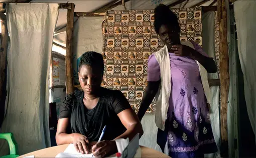 Midwife Susan Oyera, with the help of medical interpreter Grace Ezati, writes a referral for a patient who has a positive HIV test to speak with a psychologist at the Médecins Sans Frontières sexual violence and mental health clinic in the Omugo settlement in the Rhino camp extension in Uganda for refugees from South Sudan.