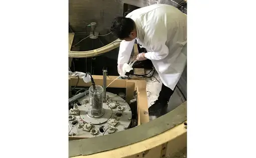 Preparing for the Chinese miniature neutron source reactor to go critical, a physicist reels up a cadmium packet that absorbs excess neutrons that make uranium atoms achieve fission. Image by Richard Stone. Ghana, 2017. 