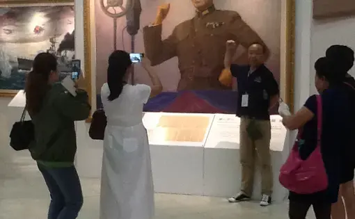 Tourists from Mainland China pose for pictures in front of a portrait of Chiang Kai-shek at the Chiang Memorial Hall in Taipei. Image by Richard Bernstein. Taiwan, 2015. Media file: img_0214.jpg