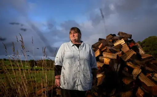 Carmall Casey stands for a portrait in her yard in Black River, Tasmania, Australia, Wednesday, July 24, 2019. From her home in rural northwest Tasmania, not far from the poppy fields that produce half the world's supply of the raw ingredients in pharmaceutical opiates, Casey seethes over a system she says pushed her and so many others into addiction. It is a system that has made opioids the cheap and easy alternative for so many Australians. Image by David Goldman. Australia, 2019.