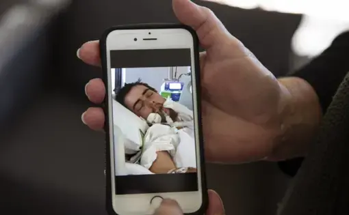 Deb Ware shows a photo she took of her son, Sam, 22, on life support from an overdose, in Fountaindale, Central Coast, Australia, Thursday, July 18, 2019. This was hardly the first overdose Sam had experienced since his addiction to pharmaceutical opioids began following a simple wisdom tooth extraction. But she wondered if it would be his last. He had somehow survived more than 60 overdoses in 12 months. Image Courtesy of David Goldman. Australia, 2019.