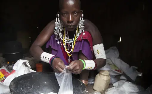 Teresia Kelele, a 27-year-old Maasai mother of two, fills bags of detergent to sell from her house for less than 50-cents each. Using money borrowed from her mother, Kelele sells phone vouchers and detergent in order to provide for her family. A generation of Maasai women in Oltukai Village are starting to sell goods despite sometimes harsh backlash from the community. Image by Sydney Combs. Tanzania, 2015.
