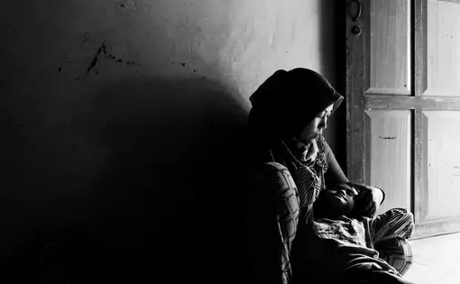 Asnia shares a tender moment with her daughter Dewi after work. Dewi is deaf and mute. Asnia works hard in the plantation to save money for her daughters treatment. Image by Xyza Cruz Bacani. Indonesia, 2018. Asnia shares a tender moment with her daughter Dewi after work. Dewi is deaf and mute. Asnia works hard in the plantation to save money for her daughters treatment. Image by Xyza Cruz Bacani. Indonesia, 2018.