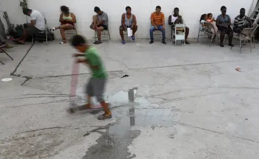 In this July 26, 2019, photo, people from Africa and Central America sit in chairs as the sun sets at El Buen Pastor shelter for migrants in Cuidad Juarez. Image by Gregory Bull. Mexico, 2019.
