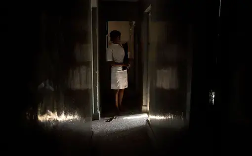 A member of the medical staff of a licensed doctor known for providing abortions stands in doorway of the operating room of his private clinic, located blocks from one of the biggest public hospitals in Lagos; in Lagos, Nigeria, August 22, 2013. They asked that their identities not be disclosed. Image by Allison Shelley. Nigeria, 2013. Media file: nigeria_abortion_projectpage_main.jpg