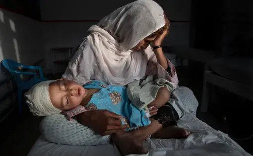 Najiba holds her nephew, Shabir, who was injured from the same bomb blast that killed his sister. Najiba watched over the children while Shabir’s mother buried her daughter. Image by Paula Bronstein. Afghanistan, 2016.