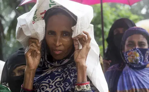 Khulna District -- Women wait in line in the rain to collect 20kgs of rice being given out by the government as part of a VGF (Vulnerable Group Feeding) program ahead of Eid-ul-fitr in a southwestern village of the country. Image by Nikita Sampath. Bangladesh, 2016. Media file: dsc_1397.jpg