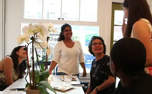 Adwa, a refugee, Kerry, founder of the Brooklyn cafe, and others celebrate at the Emma's Torch graduation ceremony. Image by Thea Piltzecker. New York City, 2018.