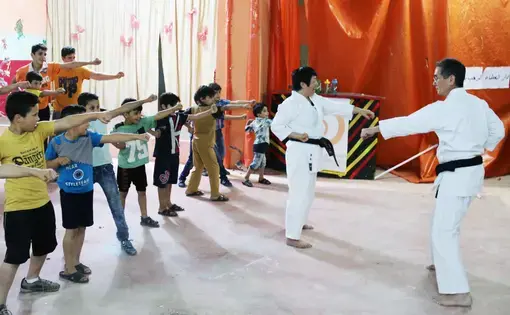 Local volunteers teach martial arts to young Syrian refugees at the Homs League Abroad in Amman. The center hopes such activities will bring positivity to the children's everyday lives. Image by Sawsan Morrar. Jordan, 2017. Local volunteers teach martial arts to young Syrian refugees at the Homs League Abroad in Amman. The center hopes such activities will bring positivity to the children's everyday lives. Image by Sawsan Morrar. Jordan, 2017.
