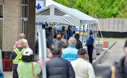 People wait in line for a COVID-19 test at a pop-up mobile Assessment Centre. Image by Bob Hilscher/Shutterstock. Canada, 2020.