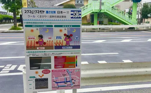 A sign next to a newly repaved road in Kumagaya explains how lighter asphalt reflects solar radiation and lowers temperatures in the city center. During the 2018 Heatwave, Kumagaya City recorded the highest-ever temperature in Japan at 41.1 degrees Celsius (106 degrees Fahrenheit), and its residents and government are adapting to the hotter world. Image by Daniel Merino. Japan, 2019.