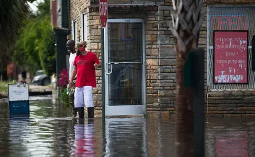 People walk out of President Market during flooding on Wednesday, May 20, 2020, in Charleston. The market is just across from the Gadsden Green public housing complex. Image by Andrew Whitaker / The Post and Courier. United States, 2020.