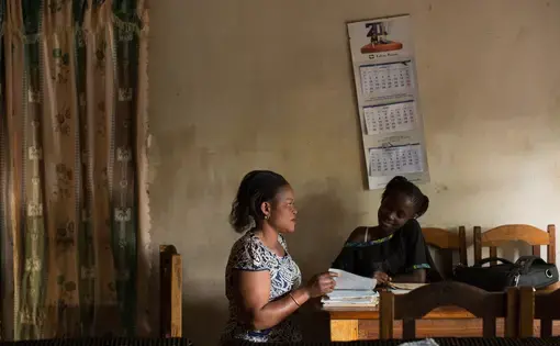 FARDC captain Fanni Katora, 34, looks over the school work of her daughter Syntiche, 10, after work at their home in Goma, D.R. Congo, November 29, 2017. Image by Allison Shelley. Democratic Republic of Congo, 2017.&nbsp;