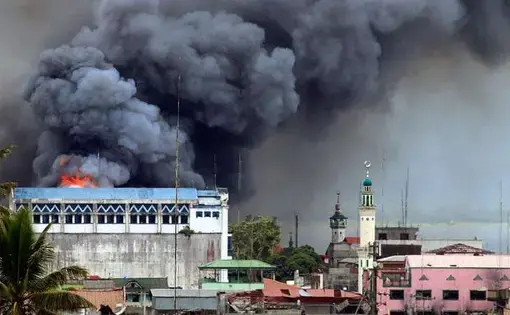 A building in Marawi is set ablaze by airstrikes carried out by the Philippine Air Force. Image by Mark Jhomel from Wikicommons. Philippines, 2017. (CC BY-SA 4.0)