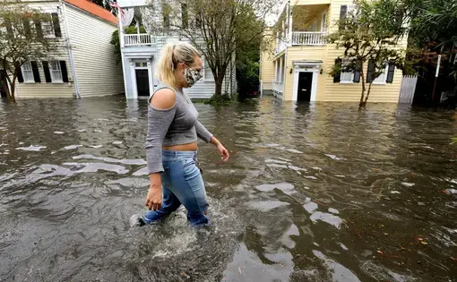 Kirstin Janssen walks through the flooded Vanderhorst Street on Friday, Sept. 25, 2020, in Charleston. Image by Grace Beahm Alford/Post and Courier Staff. United States, 2020.