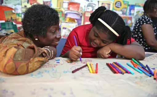 Dr. Claudette Crawford-Brown interacts with Shaniqua Long during an art therapy session at Shortwood Practising Infant, Primary and Junior High School in Kingston, Jamaica. Long's mother migrated to the United States. Image by Sabriya Simon. Jamaica.