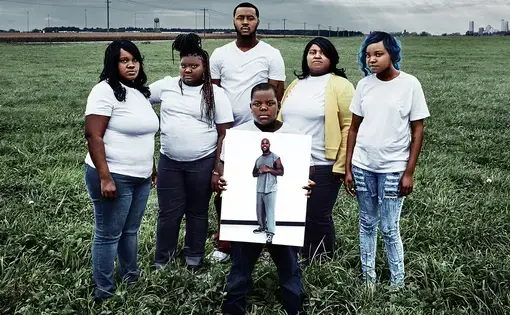 The Walker family poses with a photo of their incarcerated father and husband, Baron, in a still from Milwaukee 53206. Image courtesy of Transform Films. United States, 2016.