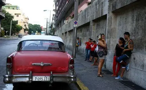 Musician Julio Cesar Onate, 27, far right, checks his email at a WiFi hotspot outside the Hotel Vedado in Havana. "There's a little more freedom in things we didn't have before," he said. "Now they give you the opportunity to get on the Internet." Image by Tracey Eaton. Cuba, 2015. Media file: 635726732155446731-julio2.jpg