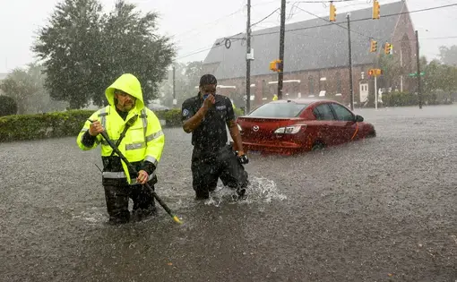 Charleston firefighter Viktor Kruzhinsky (left) uses a roof hook as a depth gauge to sound the ground in front of him while rescuing motorists trapped by floodwaters at the intersection of King and Huger streets after an intense downpour in downtown Charleston on Friday, September 25. Image by Andrew J. Whitaker / Post and Courier. United States, 2020.