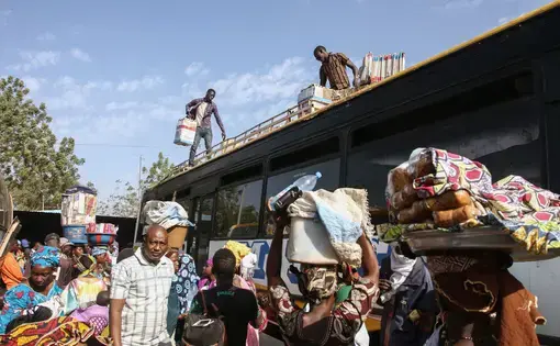Buses idle at the main bus station in Bamako, Mali. Thousands of migrants each year board buses like these bound for Gao, from where they will cross the Sahara to Algeria. Image by Anthony Fouchard. Mali, 2017.