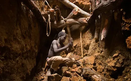 Nine-year-old Karim Sawadogo swings a pick at the bottom of a 40-foot pit at Kouékowéra. Image by Larry C. Price. Burkina Faso, 2013.