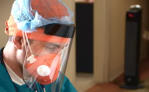 Esperanza doctor Federico Herrera, dressed in PPE, examines a COVID-19 test. Image courtesy of Esperanza Health Centers. United States, 2020.