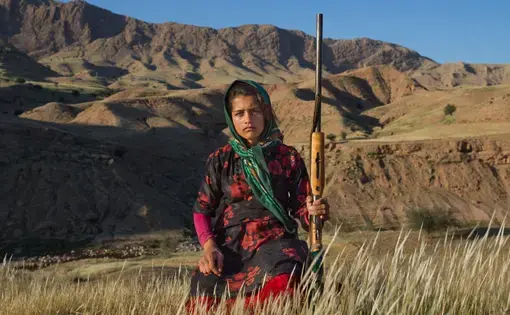 In Khuzestan Province, Masoumeh Ahmadi, 14, holds her mother’s shotgun. After a woman marries, she receives a firearm—with the approval of her husband and her father. Many women get one as a gift from their husbands after giving birth to their first son. Image by Newsha Tavakolian. Iran, 2018.