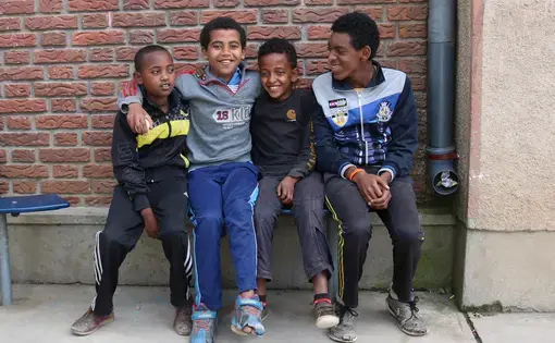 Four boys pose for a photo at Kidana Mehert Children’s Home in Addis Ababa. These boys were playing soccer together with a small ball they found. They live in the home and will continue to live there until they are 18. After they finish school they will decide to work or go to college. This children’s home allows local adoption so anyone of the kids who currently living there can be adopted. Image by Abigail Bekele. Ethiopia, 2018.