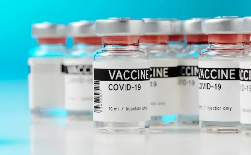 Ampoules with a COVID-19 vaccine on a laboratory bench. Image by M-Foto/Shutterstock. 2020.