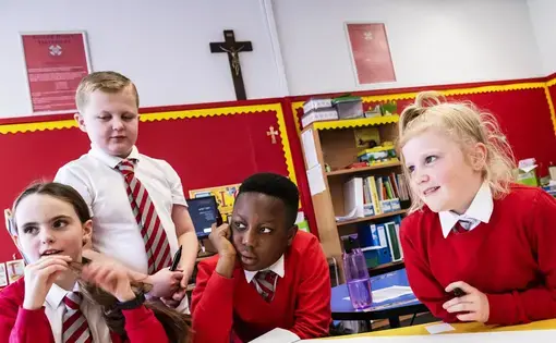From left: Holly Muir, 9, Mark Cleary, 9, Hanford Frimpong, 11, and Summer McKay, 10, all of Bridgeton, listen as Stacy Innerst, children's book, illustrator, speaks, Wednesday, Oct. 23, 2019, at Sacred Heart Primary Primary School in Glasgow, Scotland. Image by Michael M. Santiago/Post-Gazette. United Kingdom, 2019.