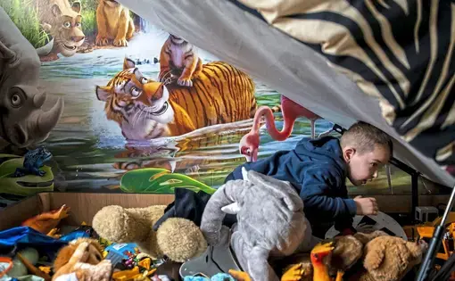 Spartacus Summers, 5, of Faifley, digs through his storage bed to look for a toy. Spartacus' bed was donated to the family two months ago by a local charity. Image by Michael M. Santiago. Scotland, 2019.