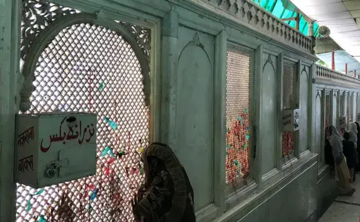Women look through the jaali surrounding the courtyard of the dargah of Qutubuddin Bakhtiyar Kaki in Delhi. Image by Nikhil Mandalaparthy. India, 2019.