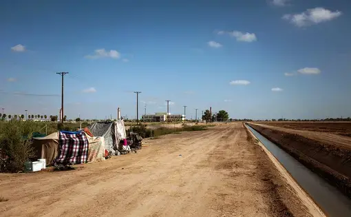 A homeless encampment near a canal in El Centro, Calif., as seen on July 24, 2020. As support services have dwindled amid the COVID-19 pandemic, some homeless people in Imperial County have resorted to bathing in irrigation canals. Homelessness looks different in different parts of the U.S., especially in rural agricultural regions such as Imperial County. Image by Anna Maria Barry-Jester/KHN. United States, 2020.