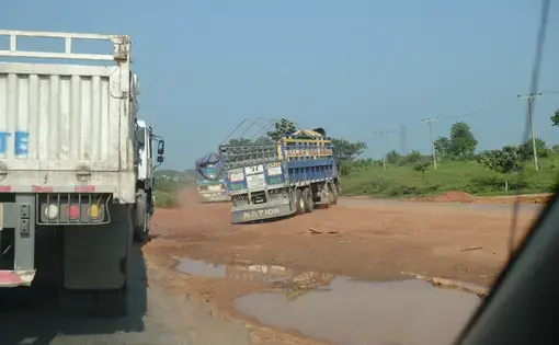 Trucks navigate a closed portion of the Abuja-Lokoja highway in Nigeria by crossing a water-filled median to the other lane. Image by T.R. Goldman. Nigeria, 2017.