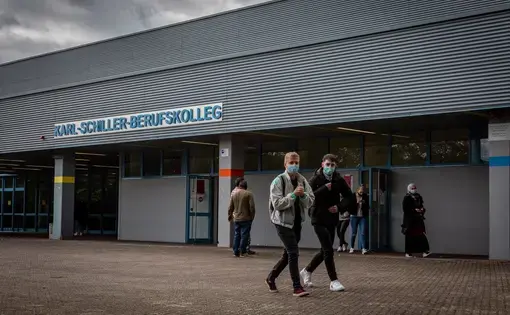 Students leave Karl-Schiller-Berufskolleg in Brühl, a secondary school outside Cologne, Germany. Students are required by the school to wear masks on schools grounds. Image by Ryan Delaney. Germany, 2020.