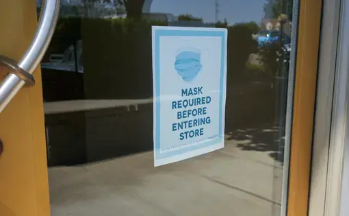 Mandatory mask policy signage at the entrance to a retail store in Oregon during the coronavirus pandemic. Image by&nbsp;Tada Images / Shutterstock. United States, 2020.