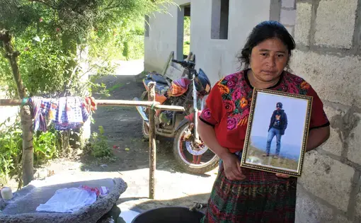 Lidia Carreto, 40, holds a framed photo of her 16-year-old son Davin, who died trying to immigrate illegally into the United States in June 2018 near Laredo, Texas. His body was repatriated to his home in the valley of Agua Blanca in San Juan, Ostuncalco. Image by Kristian Hernandez. Guatemala, 2018.