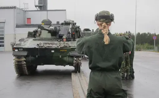 A female mechanized infantry conscript directs colleagues while learning to repair a CV90 combat vehicle. Image by Teresa Fazio. Sweden, 2018.