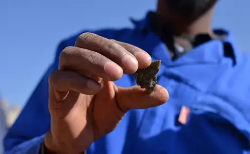 An illegal miner displays gold ore dug from an abandoned mine in Johannesburg. South Africa, 2016. Image by Mark Olalde.