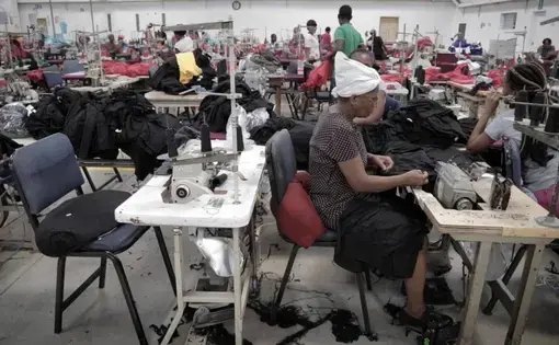 A female Haitian factory worker sews at Cleveland Manufacturing in Port-au-Prince, Haiti. The factory is among several working with two nonprofits to screen female workers for cervical cancer. Image by José A. Iglesias. Haiti, 2018.
