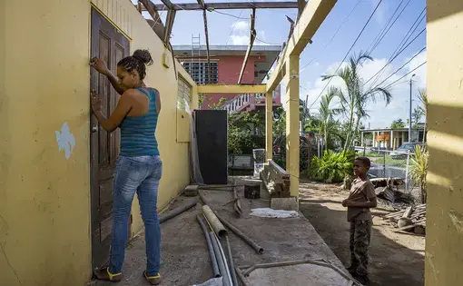 Rosalda Olma, a wife and mother to three kids, opens the front door to what remains of her home in Loiza. The entire home and contents were destroyed by the hurricane, and the family is living in a nearby school for the time being. “It’s hard getting used to these living conditions,” she said. “All five of us are trying to fit inside a single room.” Image by Ryan Michalesko. Puerto Rico, 2017.