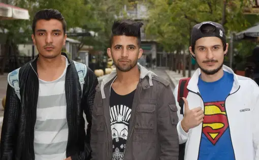 Three young refugees from Afghanistan (left, center) and Iran (right) who arrived in Greece as unaccompanied minors in 2016 pose for a photo in Victoria Square, a hub of activity for Athens's Afghan communities. Image by Divya Mishra. Greece, 2018.&nbsp;