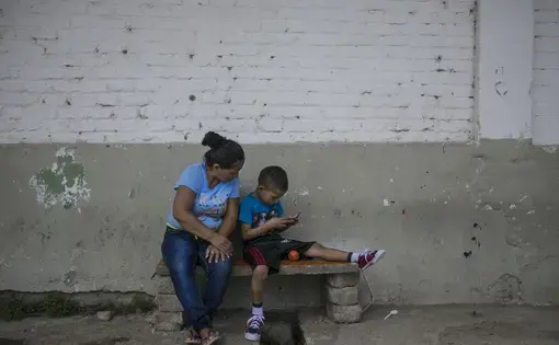 Honduran migrant Sandra and her son, Angel, have been staying at the Todo por Ellos migrant shelter in Tapachula since June. She left behind her husband, a gang member, out of fear that her children would inherit the gang life or be killed. Image by Jose Cabezas. Mexico, 2018. 