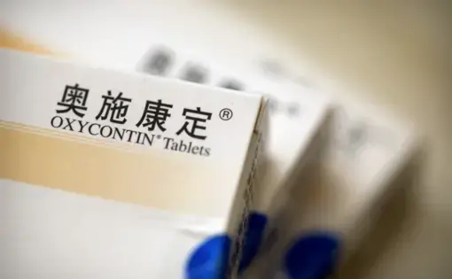 Boxes of OxyContin tablets sold in China sit on a table in southern China's Hunan province on Sept. 24, 2019. Representatives from the Sacklers' Chinese affiliate, Mundipharma, tell doctors that OxyContin is less addictive than other opioids — the same pitch that their U.S. company, Purdue Pharma, admitted was false in court more than a decade ago. Image by Mark Schiefelbein / AP Photo. China, 2019.